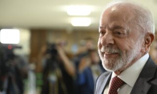 Atrás de Flávio, Lula vota em São Bernardo segurando a bandeira do Brasil